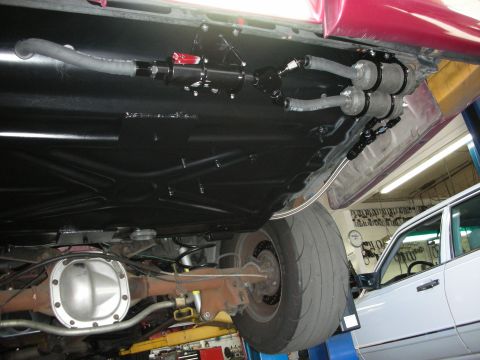 1992 Ford Crown Victoria - The underside of a vehicle shows a modified fuel system with multiple filters and lines, with another car in the background.