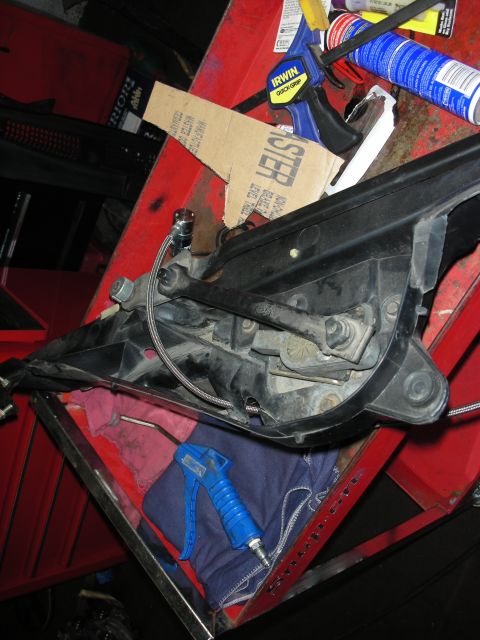 1992 Ford Crown Victoria - A car headlight assembly is disassembled and placed on a red toolbox with various tools and parts.
