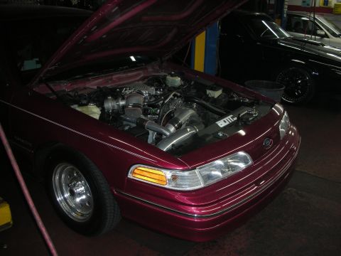1992 Ford Crown Victoria - A maroon 1992 Ford Crown Victoria is shown with its hood open, revealing an engine modified with a turbocharger.