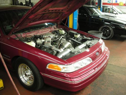 1992 Ford Crown Victoria - Customized 1992 Ford Crown Victoria engine bay with turbocharger, another car visible in the background.