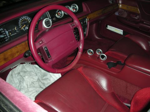 1992 Ford Crown Victoria - The interior of a car features a red steering wheel and seats, with multiple aftermarket gauges on the dashboard and console.