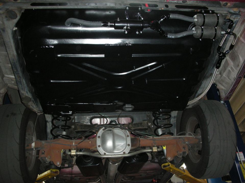 1992 Ford Crown Victoria underside, showing a freshly painted black chassis, dual fuel pumps, and rear axle