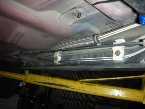 1992 Ford Crown Victoria - Underside view of a vehicle's brake and fuel lines, secured by white clips, on a lift.