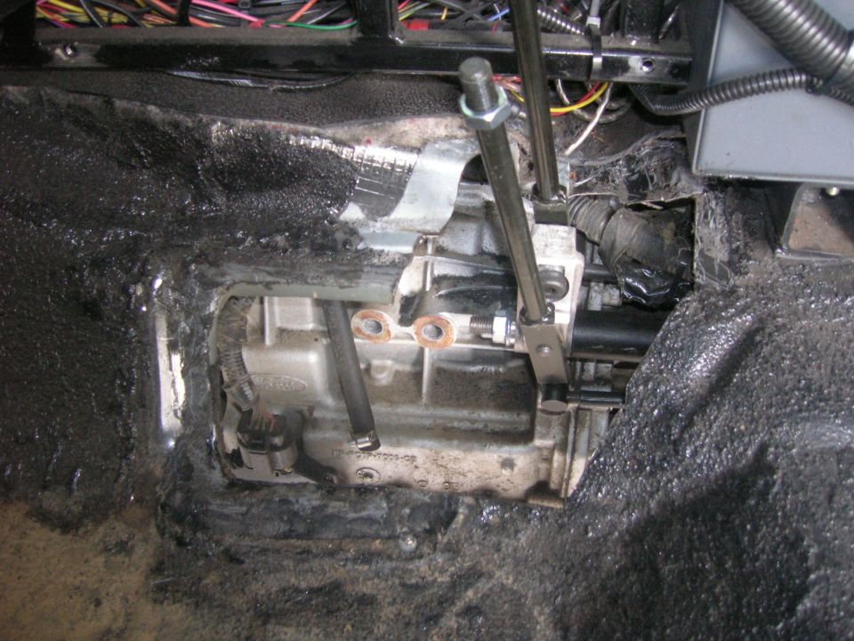 close-up of vehicle's transmission and shifter linkage, wires visible above