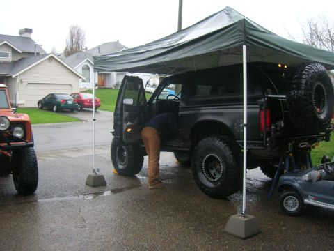 1996 Ford Bronco - A person works on the interior of a black Ford Bronco with aftermarket modifications.