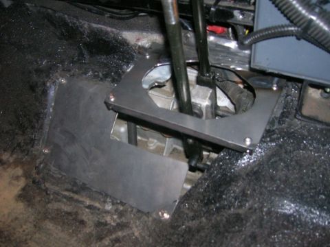 1996 Ford Bronco - The interior floor of a vehicle is shown, focusing on the shifter mechanism and surrounding metalwork.
