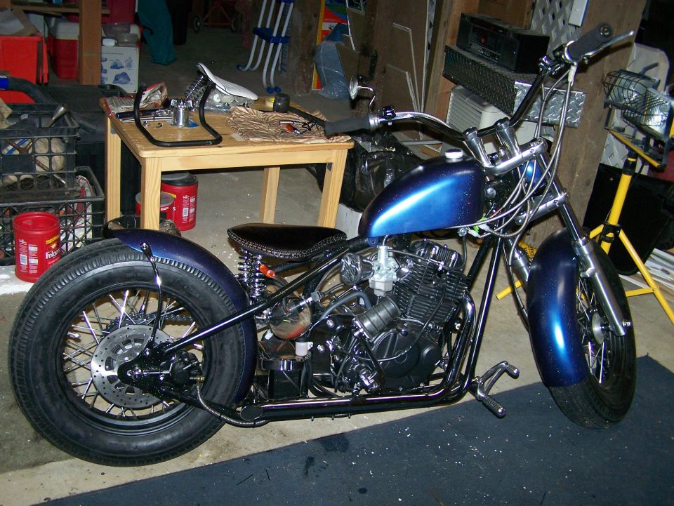 Blue custom motorcycle with wide rear tire and ape hanger handlebars