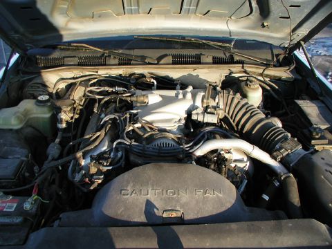 1993 Ford Crown Victoria - Engine bay with "CAUTION FAN" cover and various hoses and components.