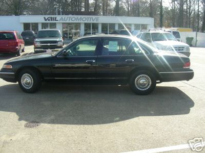 1997 Ford Crown Victoria - Side view of a 1997 Ford Crown Victoria at a dealership with other vehicles present.