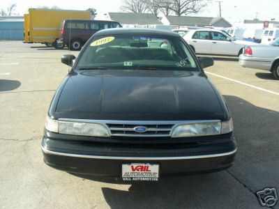 1997 Ford Crown Victoria - A black 1997 Ford Crown Victoria is parked in a lot with other vehicles visible in the background.