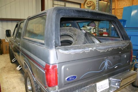 1986 Ford Bronco - Rear view of a 1986 Ford Bronco, showing spare tires loaded in the back.
