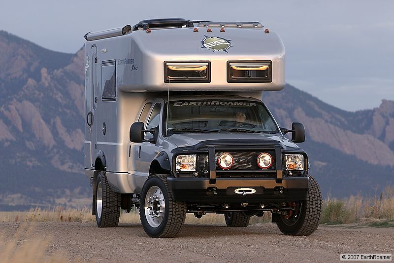 EarthRoamer camper truck with a large RV body on the back, parked on a dirt road with mountains in the background