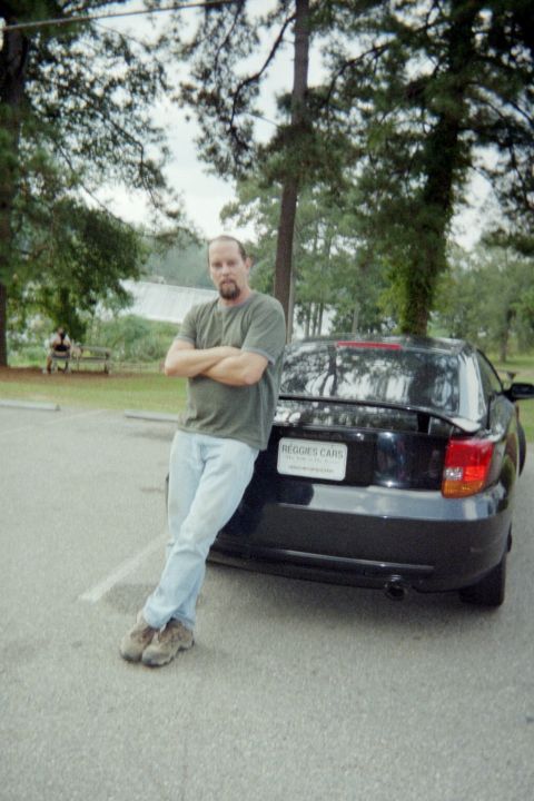 2000 Toyota Celica - A man poses next to a black Toyota Celica, which appears to be a 2003 model based on its body style.