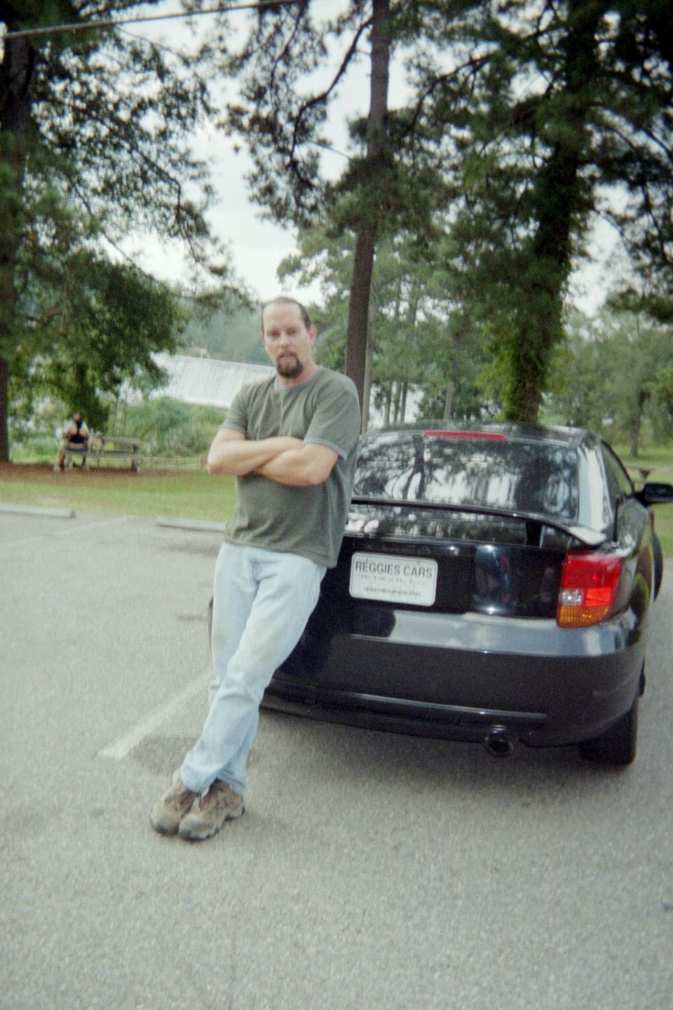 Man leaning on a black Toyota Celica. License plate reads REGIES CARS
