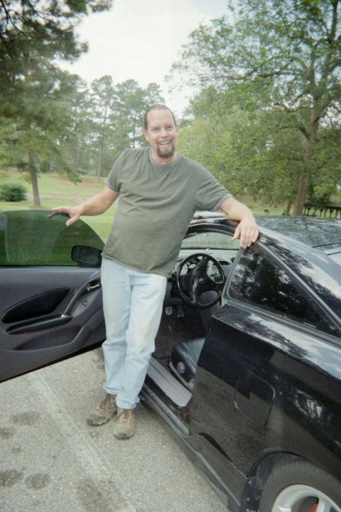 2000 Toyota Celica - A man poses next to a black 2000 Toyota Celica with the driver's door ajar.