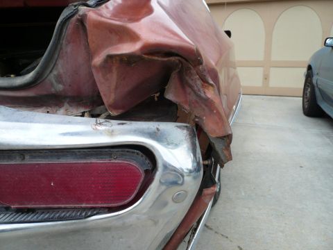 1975 Ford Ranchero - The rear of a vehicle shows significant damage to the body and bumper, with another car visible in the background.