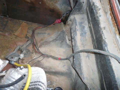 1975 Ford Ranchero - The interior floor of a vehicle shows exposed wiring and a yellow hose, with some debris scattered around.