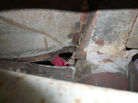1975 Ford Ranchero - The underside of a vehicle shows significant rust and a small red item lodged in a crevice.