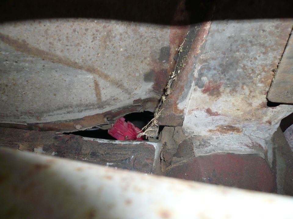 Close-up of rusted metal frame with a red object visible through a gap