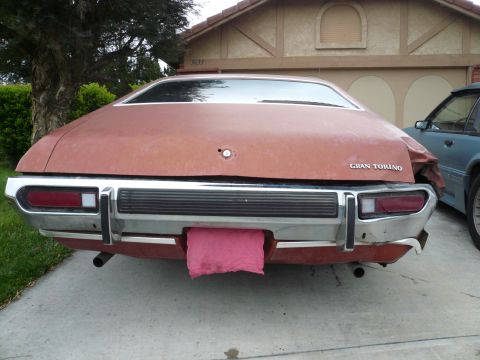1975 Ford Ranchero - The rear of a 1975 Ford Gran Torino shows damage and a pink cloth hanging from the bumper.