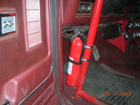 1985 Ford Bronco - Interior view of a red vehicle, showing a fire extinguisher mounted on the side panel.