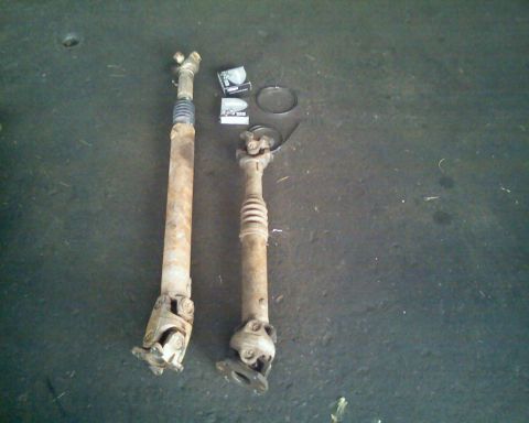 1996 Ford Bronco - Two driveshafts, one longer than the other, are shown on a concrete surface.