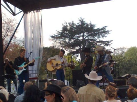 1991 Ford Crown Victoria - A live music performance takes place on an outdoor stage with a band playing instruments.
