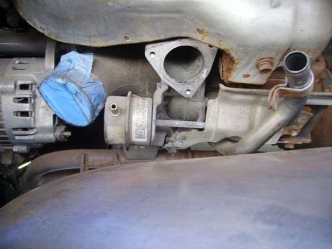 1969 MINI Cooper - Close-up view of engine parts, including an alternator and a turbocharger, with a blue cover on a pipe.