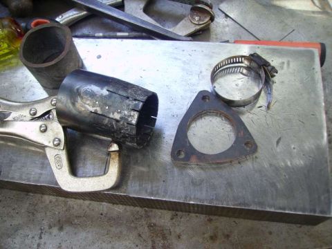 1969 MINI Cooper - Close-up of exhaust pipe modification parts including a flange and hose clamp, held by a locking plier.