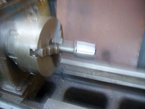 1969 MINI Cooper - A metal component is being machined on a lathe chuck in a workshop.