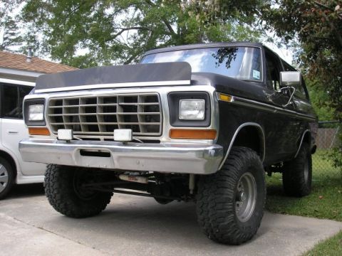 1979 Ford Bronco - This lifted Ford Bronco sits parked in a driveway, its off-road tires and stance.
