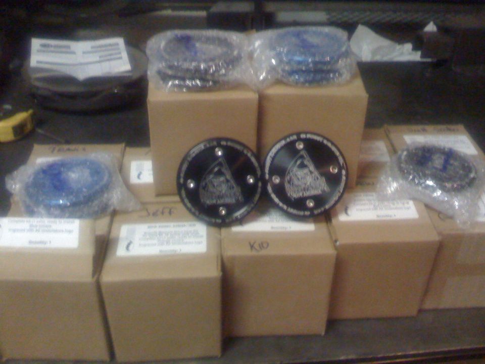 Two black drive flanges with engraved logos sit atop boxes