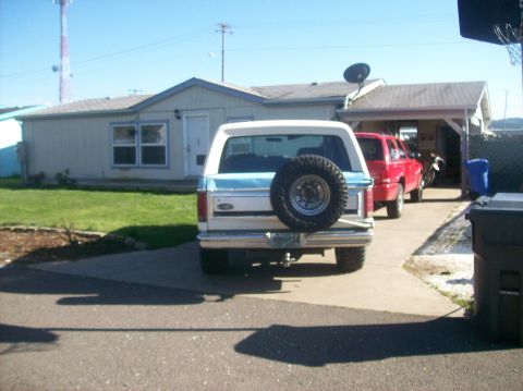 1982 Ford Bronco - Rear view of a 1982 Ford Bronco parked in a driveway with a red SUV nearby.
