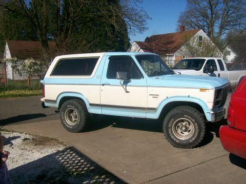 1982 Ford Bronco - A two-tone blue and white Ford Bronco is parked in a driveway next to a white pickup truck.