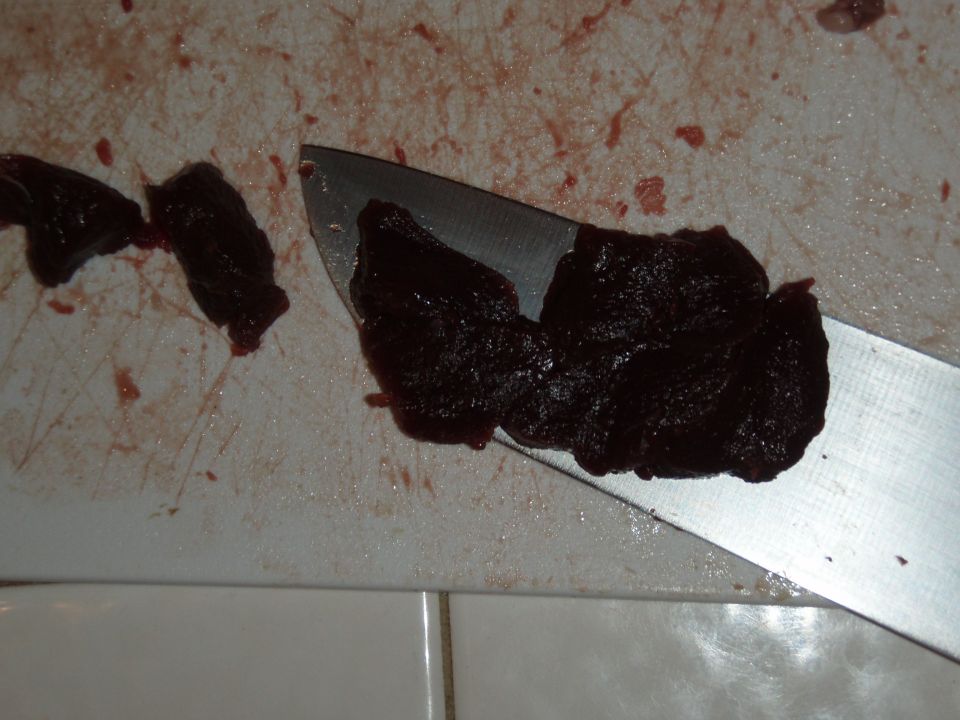 Chopped dark meat on a cutting board next to a knife blade