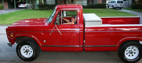 1975 International Scout II - A red 1975 International Scout II pickup truck is shown from the side with a young driver behind the wheel.