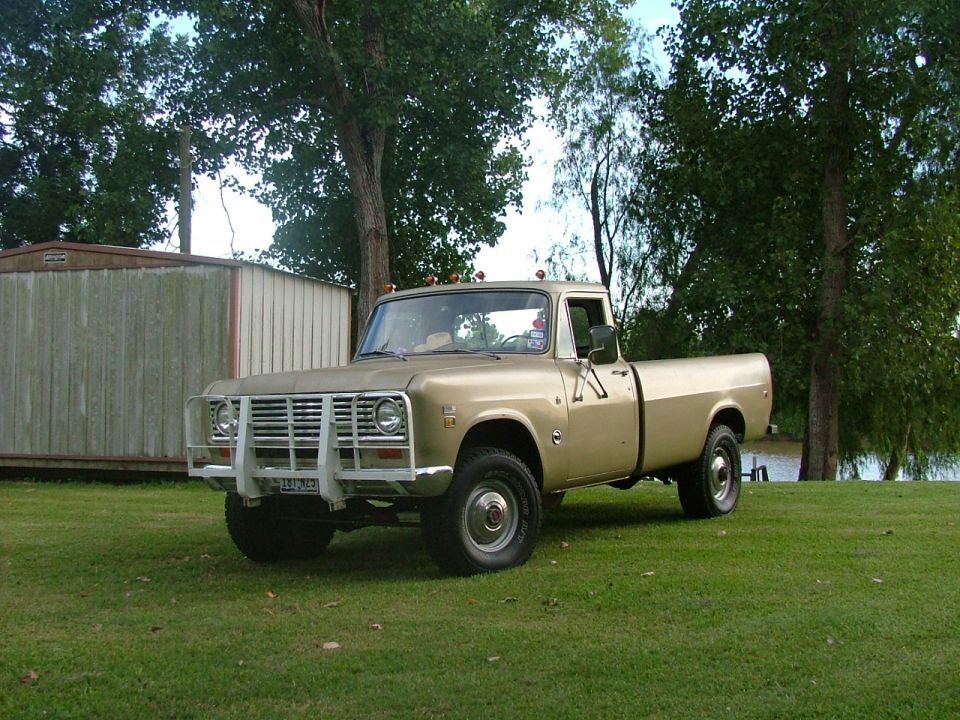Tan International pickup truck parked on grass near a shed and a body of water