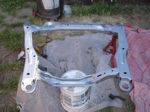 1995 Ford Taurus - Car subframe assembly, likely for a sedan, outdoors with tools nearby.