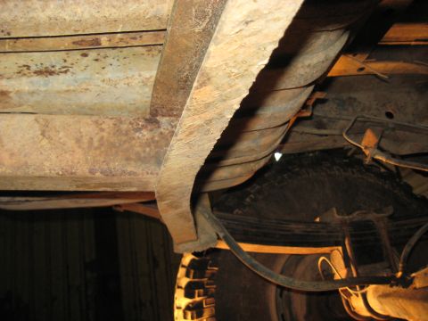 1978 Ford Bronco - The underbody of this vehicle displays significant rust on its frame and components, with a tire visible.