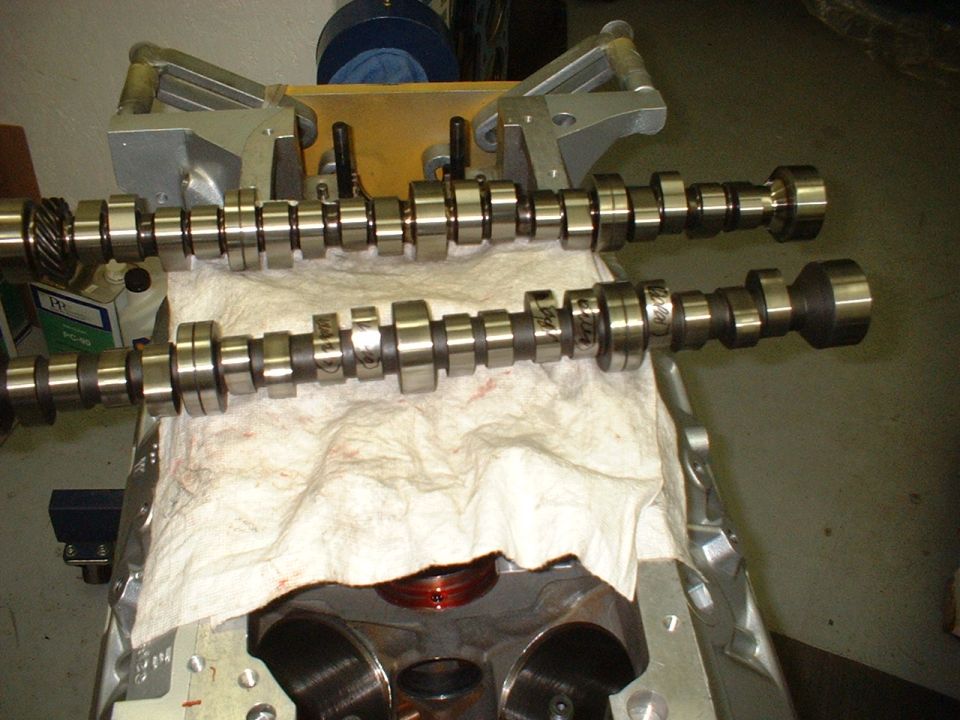 Two camshafts on paper towels resting on a bare engine block during a rebuild