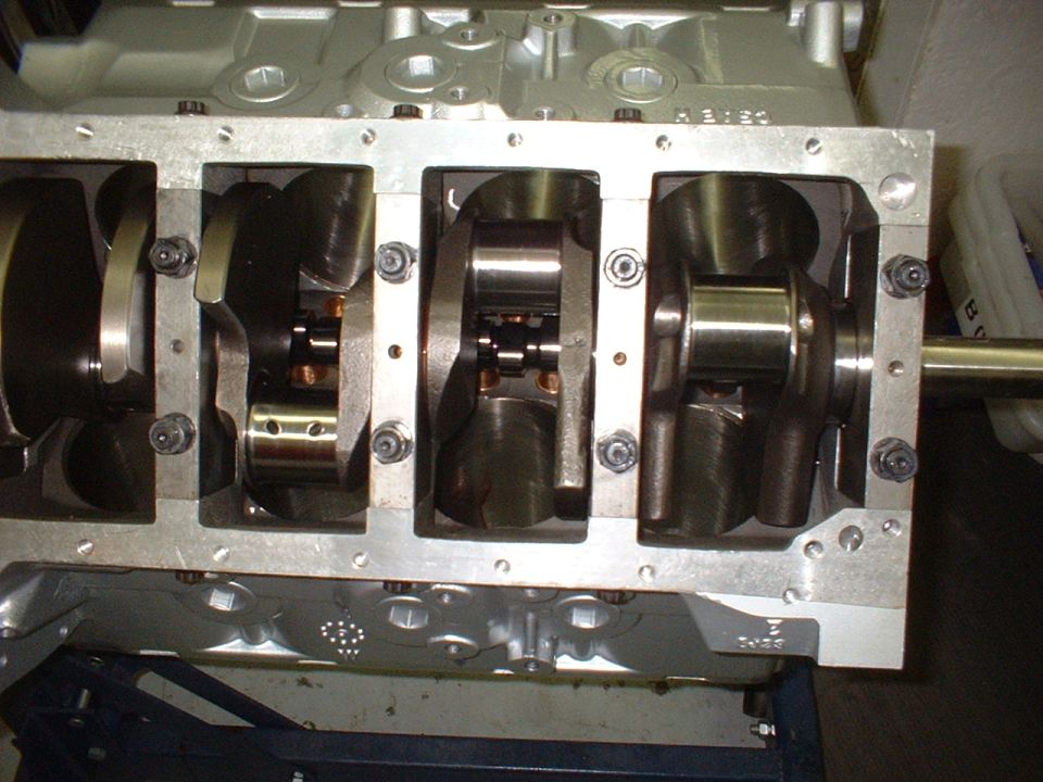 Close-up of an engine block showing the crankshaft and connecting rods inside. Some text is visible on the block