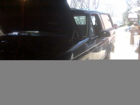 1995 Ford Bronco - A dark 1995 Ford Bronco is shown with its hood open, viewed from the front three-quarter angle.