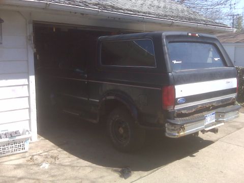 1995 Ford Bronco - The rear passenger side of a black 1995 Ford Bronco is parked in a garage with the rear bumper and taillight visible. The vehicle has a whi…