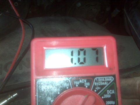 1995 Ford Bronco - A red digital multimeter displays a reading of 1.07 volts. The multimeter is connected to a vehicle's electrical system via red and black w…