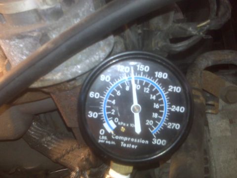 1995 Ford Bronco - A close-up view of a compression tester gauge connected to what appears to be an engine. The gauge reads approximately 120 PSI, with markin…
