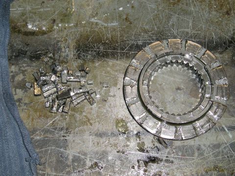 1986 Toyota Hilux - A pile of broken clutch plates and a damaged clutch disc are on a dirty, scratched metal surface. A blue cloth is visible on the left side…