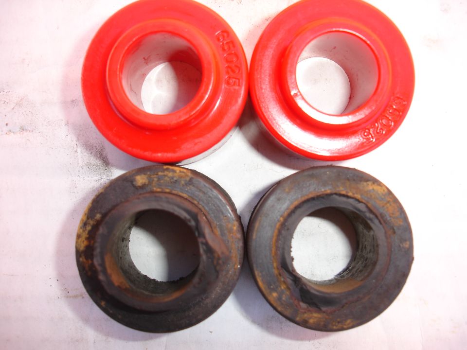 Photo comparing new red poly bushings to worn rubber bushings