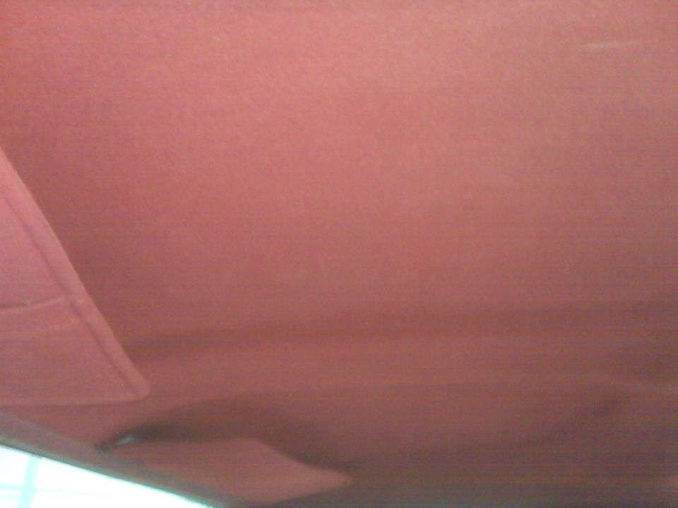 Red fabric headliner and folded sun visor inside a vehicle cabin