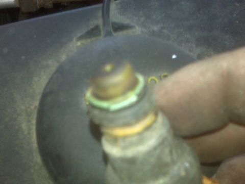 1995 Ford Bronco - A close-up shot shows a hand holding a fuel injector with a green O-ring. The injector is positioned over a dark, textured surface, possibl…