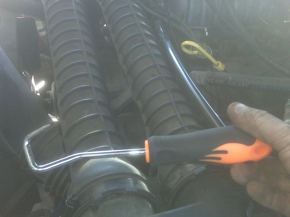 Hand holding a tool over a ribbed engine component